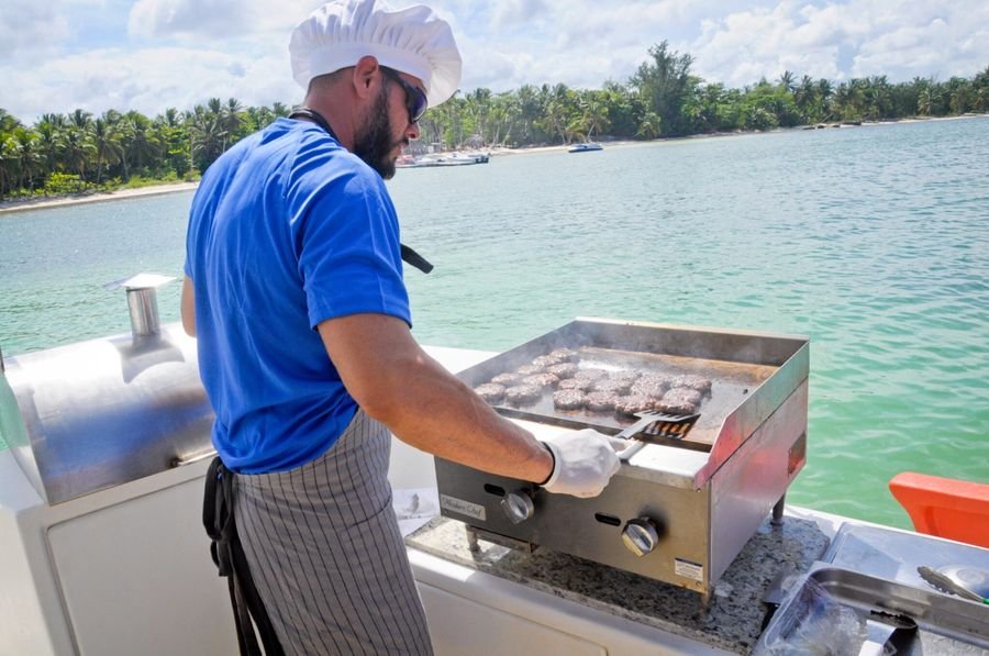 Chef preparando hamburguesas en la parrilla a bordo